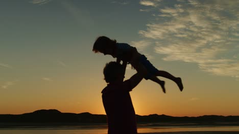 Silhouette-von-Vater-und-Sohn-spielen-zusammen-am-Strand.