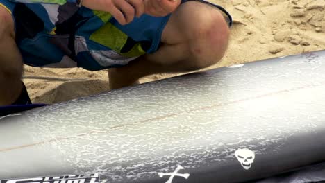 Applying-wax-on-a-surfboard