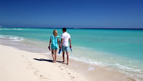 Junges-Paar-mit-Hausschuhen-zu-Fuß-entlang-des-Strandes