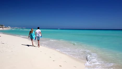 Junges-Paar-mit-Hausschuhen-zu-Fuß-entlang-des-Strandes