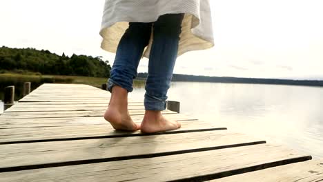 Close-up-on-woman's-feet-standing-on-jetty-above-lake