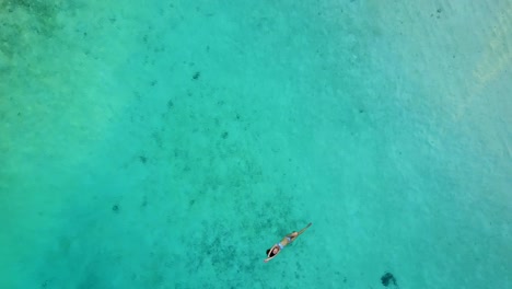 Aerial-view-of-an-attractive-woman-in-a-bikini-floating-in-crystal-clear-sea.-Pretty-beatiful-girl-swimming-in-Indian-ocean