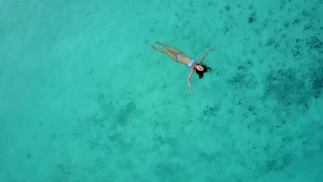 Vista-aérea-de-una-atractiva-mujer-en-un-bikini-flotando-en-el-mar-de-aguas-cristalina.-Bonita-hermosa-chica-nadando-en-el-Océano-Índico