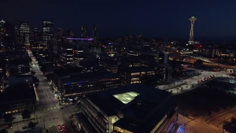 Aerial-of-Downtown-Seattle-Lit-at-Night-with-Cars-Driving-on-City-Streets