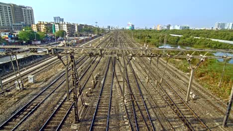 Time-lapse-shot-of-the-moving-suburban-(local)-trains,-on-the-one-side-there's-protected-mangrove-forest-(wetland)-and-all-other-sides-are-covered-with-city-buildings,-Mumbai,-India