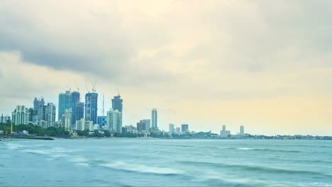 Tiro-de-lapso-de-tiempo-la-noche-de-las-nubes-pasando-sobre-los-edificios-de-ciudad-(skyline-de-la-ciudad)-la-mayoría-de-ellos-está-en-construcción-al-mar-Arábigo-en-el-primero-plano,-Mumbai,-India