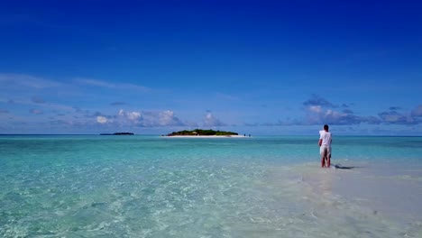 v03944-Aerial-flying-drone-view-of-Maldives-white-sandy-beach-2-people-young-couple-man-woman-romantic-love-on-sunny-tropical-paradise-island-with-aqua-blue-sky-sea-water-ocean-4k