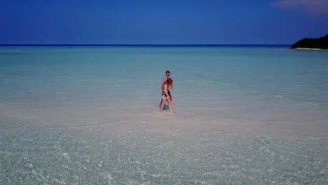 v03867-vuelo-drone-vista-aérea-de-Maldivas-playa-2-personas-pareja-hombre-mujer-amor-romántico-en-la-isla-de-paraíso-tropical-soleado-con-cielo-azul-aqua-agua-mar-4k