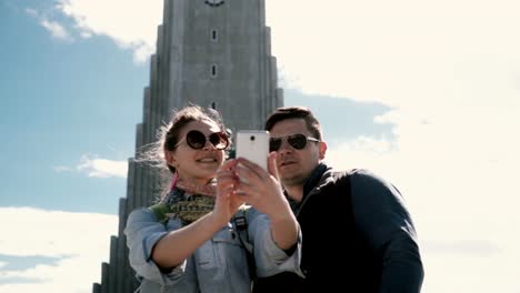 Junge-Brautpaar-der-Selfie-Aufnahme-auf-Smartphone-in-der-Nähe-der-Kirche-Hallgrímskirkja-in-Reykjavík,-Island