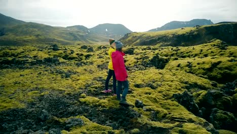 Vista-aérea-de-dos-mujeres-caminando-por-los-campos-de-lava-en-Islandia.-Turistas-disfrutando-del-paisaje,-explorando-el-territorio