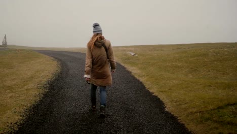 Vista-trasera-del-joven,-paseando-por-el-campo-solo.-Elegante-mujer-explorando-la-naturaleza-de-Islandia