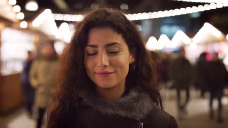 Retrato-de-sonriente-mujer-disfrutando-de-mercado-de-Navidad-en-la-noche