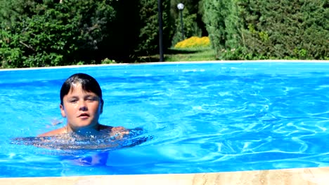 Young-boy-in-swimming-pool-smiling-to-a-camera