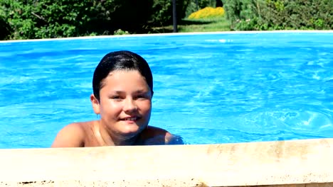 Young-boy-in-swimming-pool-smiling-to-a-camera