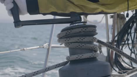 Sailor-man-using-sail-winch-and-rope-while-sailing-on-yacht-in-sea-close-up