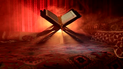 Open-holy-book-of-Muslims-on-stand-on-eastern-carpet-with-dark-toned-foggy-background.-Muslim-religion-concept.-Selective-focus.-Slider-shot.