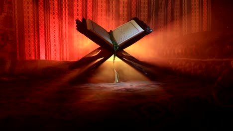 Open-holy-book-of-Muslims-on-stand-on-eastern-carpet-with-dark-toned-foggy-background.-Muslim-religion-concept.-Selective-focus.-Slider-shot.