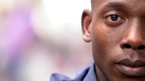 close-up-on-Young-black-african-man-staring-at-camera-outdoor--half-face