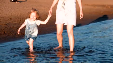 Mom-and-girl-playing-on-the-beach-of-the-river-at-sunset-and-swim.