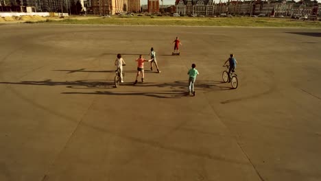 Teenagers-with-back-to-the-camera-riding-on-urban-wheeled-vehicles.-Bird's-eyes-view