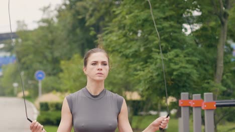 Mujer-deportista-con-comba-para-ejercicio-al-aire-libre-en-el-parque-de-verano