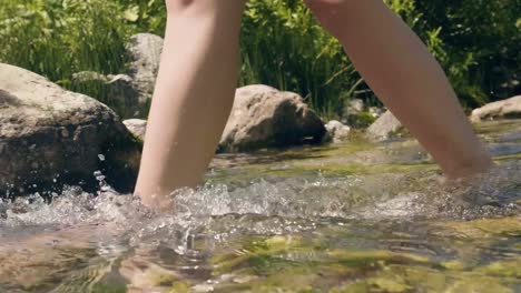 Female-legs-walking-in-river-shallow-and-transparent-water-background
