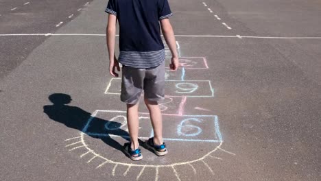 Junge-springt-Spiel-Himmel-und-Hölle-auf-der-Straße.-Close-up-Beine.