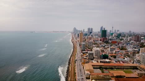 Tolle-Luftaufnahme-von-Colombo,-Sri-Lanka.-Drohne-fliegt-über-belebten-Straße,-Meereswellen-und-modernen-asiatischen-Architektur