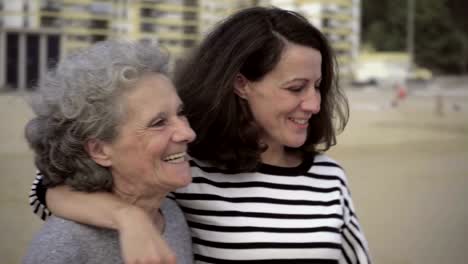 Smiling-mature-daughter-kissing-and-embracing-senior-mother.