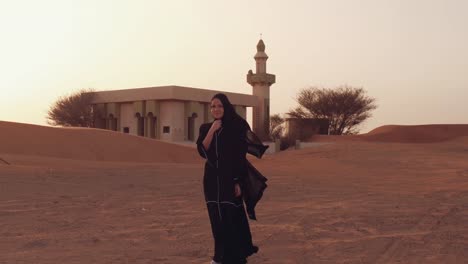 Mujer-musulmana-de-pie-cerca-de-la-mezquita-en-el-desierto.-Viento-fuerte-Paz-de-Oriente-Medio-sin-guerra