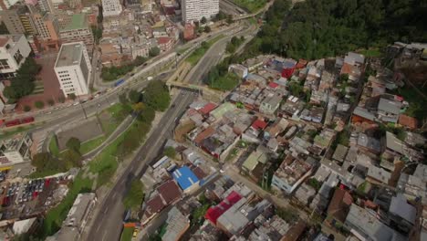 Aerial-tilting-up-from-shanty-town-to-downtown-office-buildings-in-Bogota,-Colombia