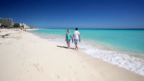 Young-couple-with-slippers-walking--along-the--beach