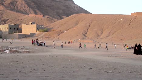 Boys-and-men-playing-soccer-in-the-evening-on-a-sand-field-in-Tamegroute