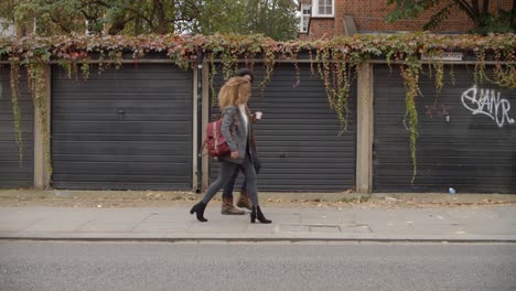 Stylish-Young-Couple-Walking-Past-Garages-On-City-Street