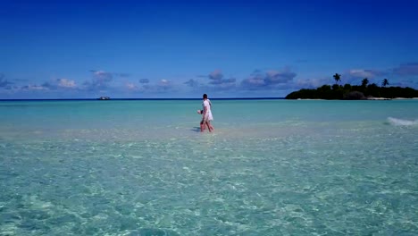 v03913-Aerial-flying-drone-view-of-Maldives-white-sandy-beach-2-people-young-couple-man-woman-romantic-love-on-sunny-tropical-paradise-island-with-aqua-blue-sky-sea-water-ocean-4k