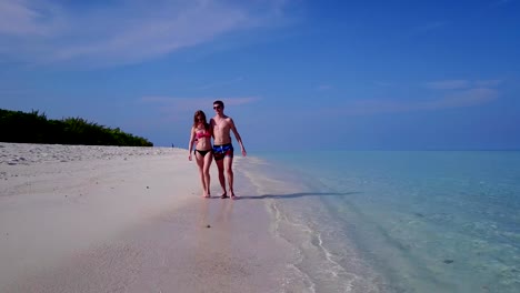 v03872-Aerial-flying-drone-view-of-Maldives-white-sandy-beach-2-people-young-couple-man-woman-romantic-love-on-sunny-tropical-paradise-island-with-aqua-blue-sky-sea-water-ocean-4k