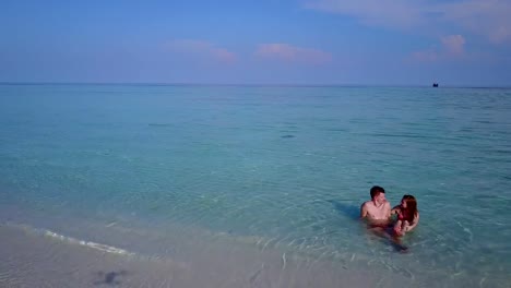 v03974-Aerial-flying-drone-view-of-Maldives-white-sandy-beach-2-people-young-couple-man-woman-romantic-love-on-sunny-tropical-paradise-island-with-aqua-blue-sky-sea-water-ocean-4k