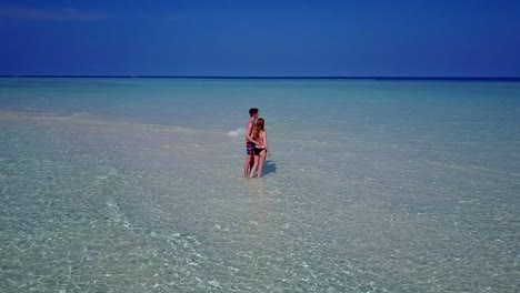 v03896-Aerial-flying-drone-view-of-Maldives-white-sandy-beach-2-people-young-couple-man-woman-romantic-love-on-sunny-tropical-paradise-island-with-aqua-blue-sky-sea-water-ocean-4k