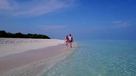 v03996-fliegenden-Drohne-Luftaufnahme-der-Malediven-weißen-Sandstrand-2-Personen-junges-Paar-Mann-Frau-romantische-Liebe-auf-sonnigen-tropischen-Inselparadies-mit-Aqua-blau-Himmel-Meer-Wasser-Ozean-4k