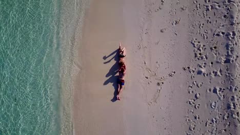 v03880-fliegenden-Drohne-Luftaufnahme-der-Malediven-weißen-Sandstrand-2-Personen-junges-Paar-Mann-Frau-romantische-Liebe-auf-sonnigen-tropischen-Inselparadies-mit-Aqua-blau-Himmel-Meer-Wasser-Ozean-4k