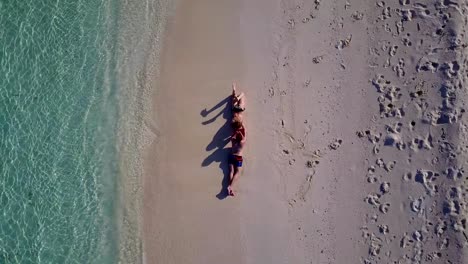 v03880-Aerial-flying-drone-view-of-Maldives-white-sandy-beach-2-people-young-couple-man-woman-romantic-love-on-sunny-tropical-paradise-island-with-aqua-blue-sky-sea-water-ocean-4k