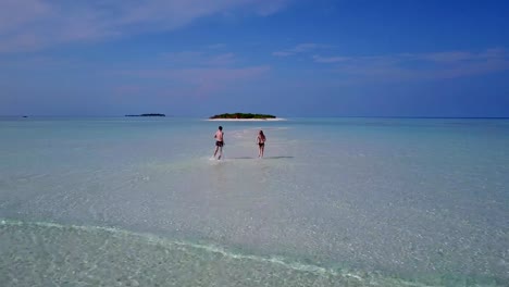 v03964-Aerial-flying-drone-view-of-Maldives-white-sandy-beach-2-people-young-couple-man-woman-romantic-love-on-sunny-tropical-paradise-island-with-aqua-blue-sky-sea-water-ocean-4k