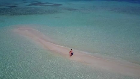 v03870-Aerial-flying-drone-view-of-Maldives-white-sandy-beach-2-people-young-couple-man-woman-romantic-love-on-sunny-tropical-paradise-island-with-aqua-blue-sky-sea-water-ocean-4k