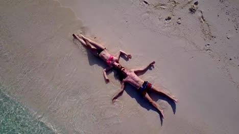 v03869-vuelo-drone-vista-aérea-de-Maldivas-playa-2-personas-pareja-hombre-mujer-amor-romántico-en-la-isla-de-paraíso-tropical-soleado-con-cielo-azul-aqua-agua-mar-4k