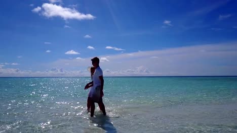 v03948-Aerial-flying-drone-view-of-Maldives-white-sandy-beach-2-people-young-couple-man-woman-romantic-love-on-sunny-tropical-paradise-island-with-aqua-blue-sky-sea-water-ocean-4k