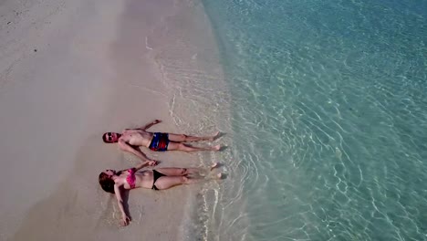 v03975-Aerial-flying-drone-view-of-Maldives-white-sandy-beach-2-people-young-couple-man-woman-romantic-love-on-sunny-tropical-paradise-island-with-aqua-blue-sky-sea-water-ocean-4k