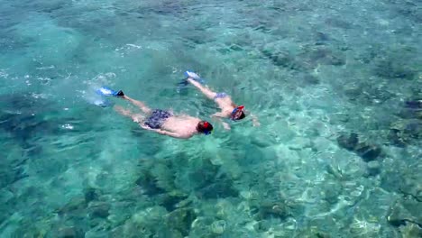 v04071-vista-aérea-de-drone-volando-de-Maldivas-playa-2-personas-pareja-joven-hombre-mujer-snorkel-natación-buceo-en-la-isla-de-paraíso-tropical-soleado-con-cielo-azul-aqua-agua-mar-4k