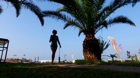 The-girl-walk-on-the-beach-under-a-palm-tree