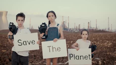 Salvar-la-planta.-Niños-pequeños-sosteniendo-carteles-de-pie-cerca-de-una-refinería-con-máscaras-de-gas