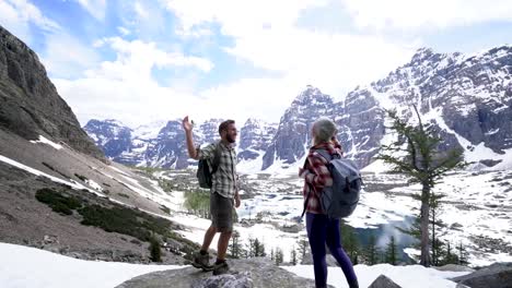 Pareja-senderismo-en-las-montañas-Rocosas-canadienses-llegar-a-la-cima-de-la-montaña-y-dar-un-alta-cinco-para-celebrar